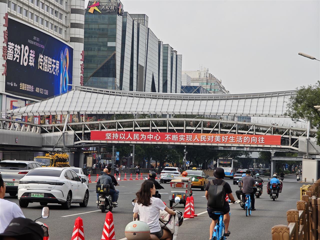九三阅兵前一日的长安大街：市民乘公交提前感受氛围，小学生姐妹在花坛前敬礼拍照
