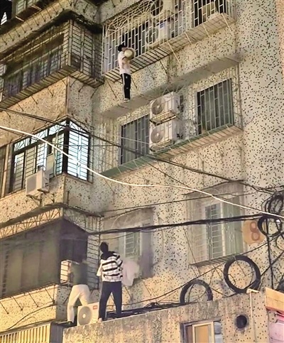 男孩卡在四楼防盗网上 白衣小伙爬窗托举助其脱险